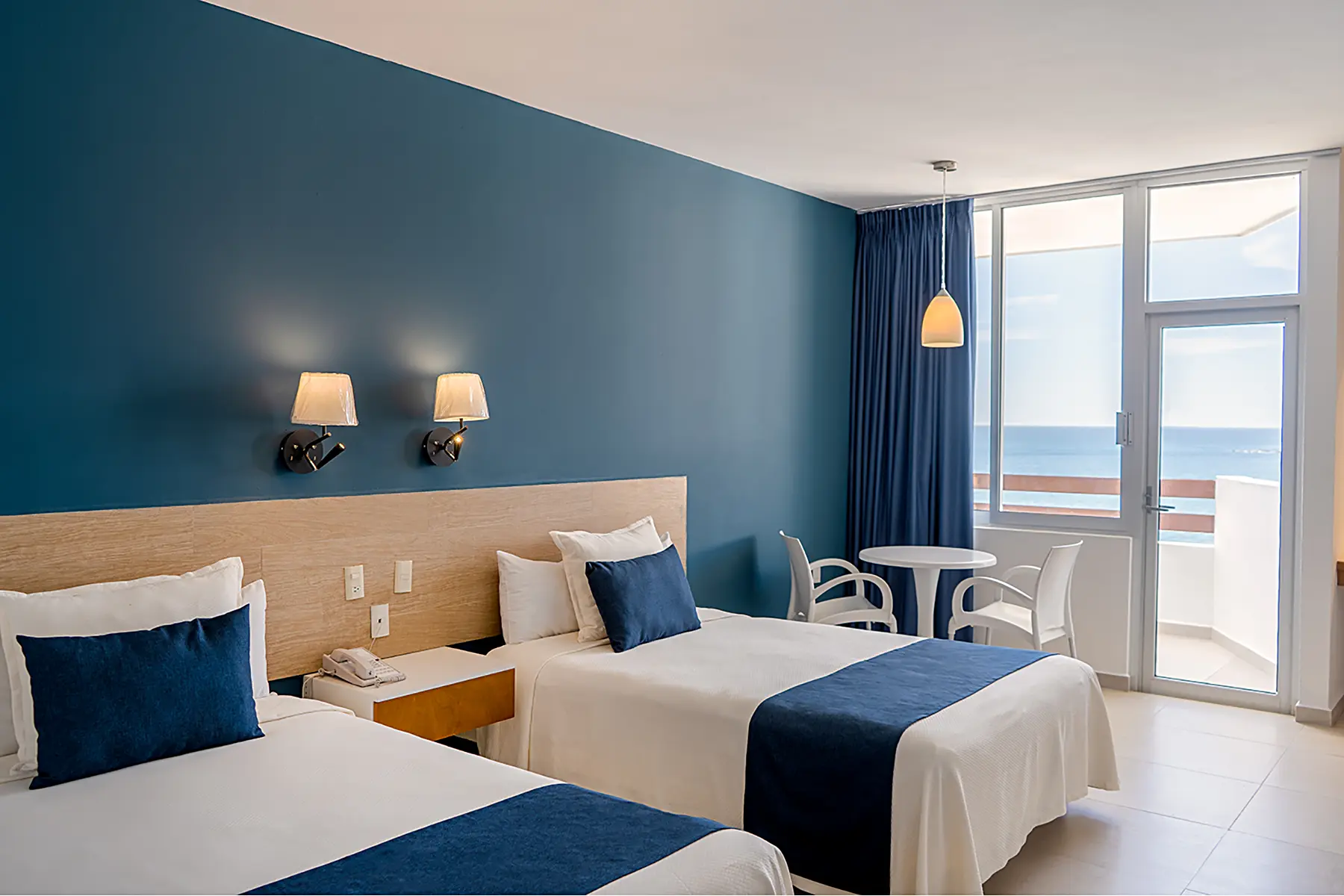 Habitación standar con balcón y vista al mar, dos camas matrimoniales, mesa con dos sillas del hotel oceano palace Mazatlán